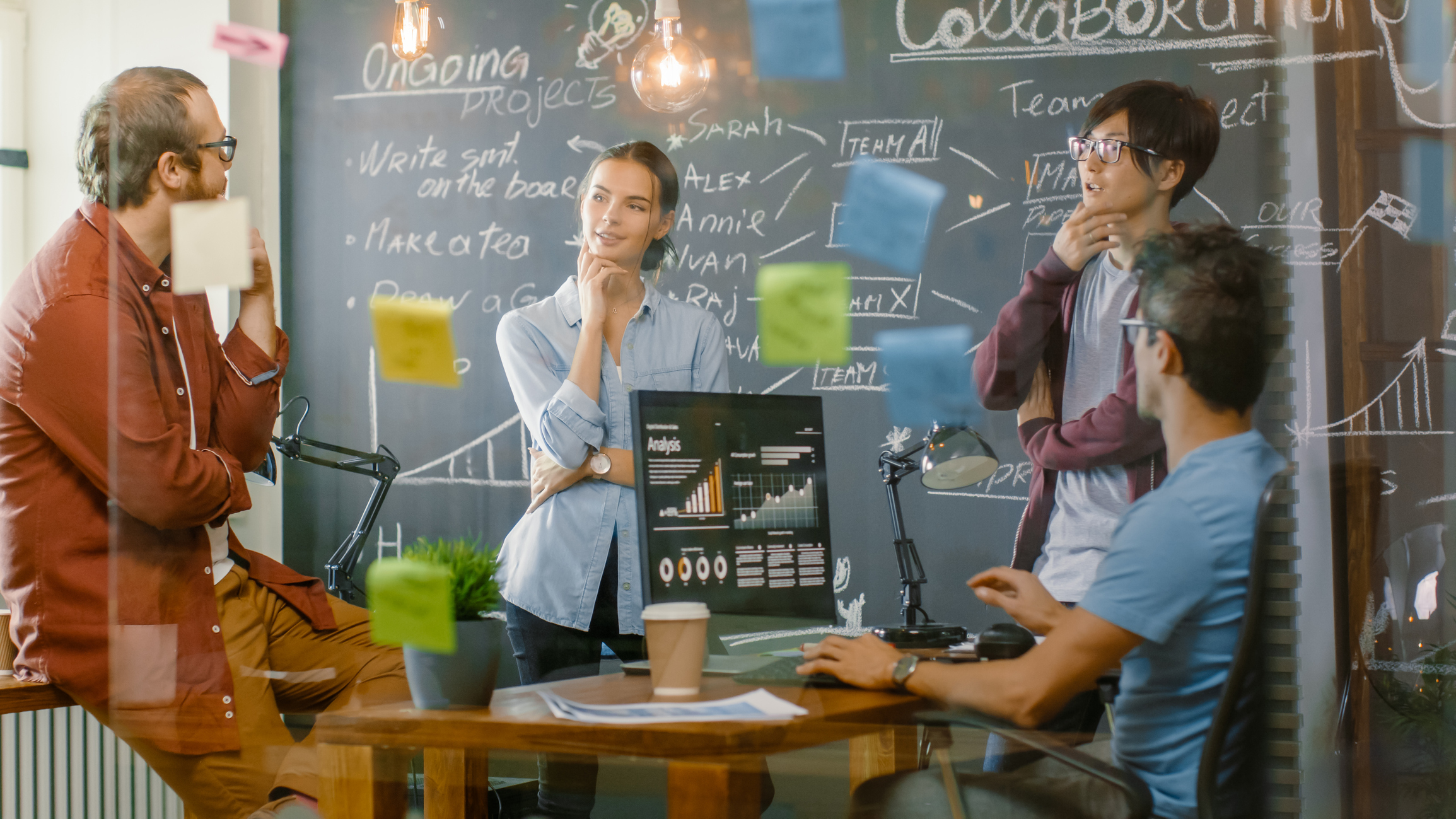 Diverse Team of Young Developers Draw Work Plan on a Blackboard Wall, Have Heated Discussion. Creative Office Space with Stylishly Dressed People.