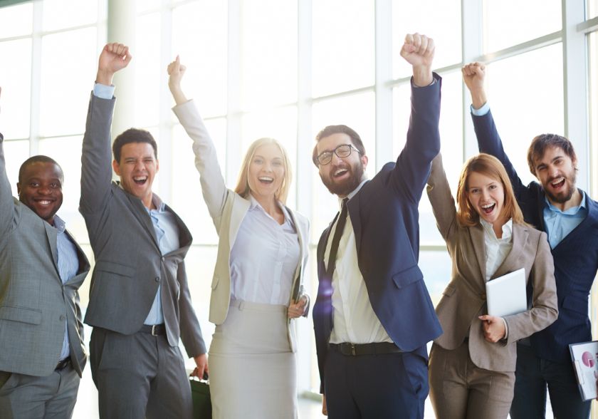 Equipe de negócios comemorando um resultado bem-sucedido com sorrisos e braços levantados após uma sprint no scrum bem sucedida