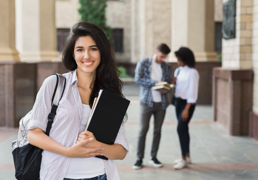 Estudante sorrindo em ambiente universitário, representando educação como caminho para realização de sonhos e conquistas pessoais.